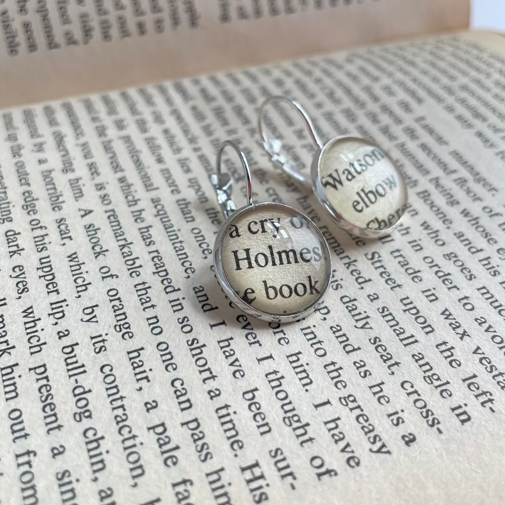 Pair of earrings with 'Holmes' and 'Watson' text on a book page background