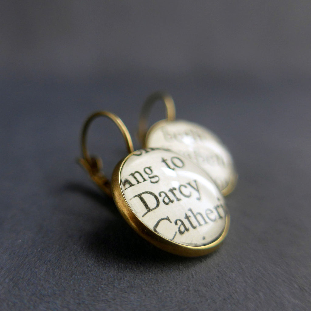 Bronze plated round earrings customised with glass and paper from pride and prejudice. one earring shows elizabeth and the other earring shows darcy. 