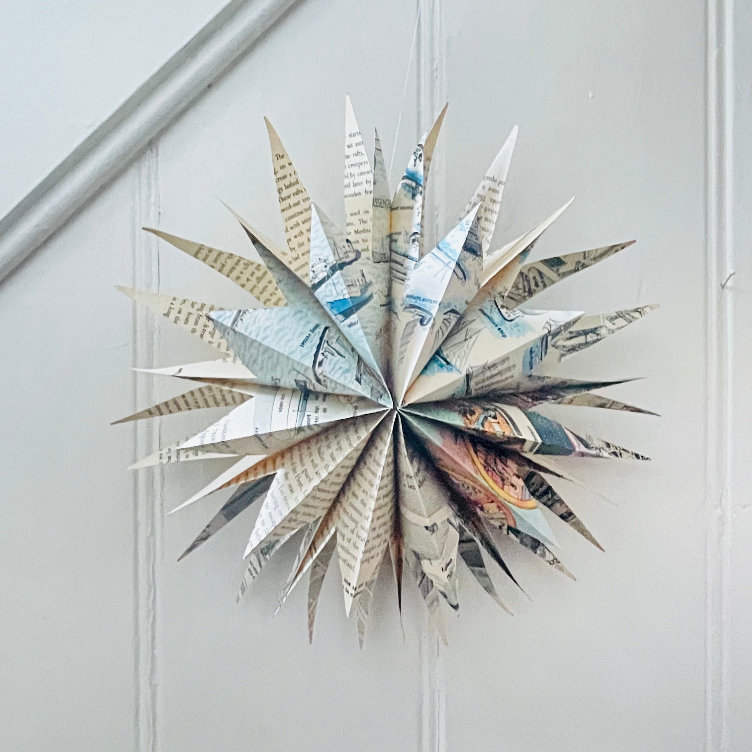 Star-shaped decorative item made from folded paper on a white wall