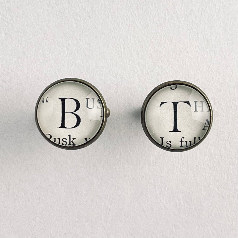 Two round cufflinks with vintage-style text from a real book, on a white background
