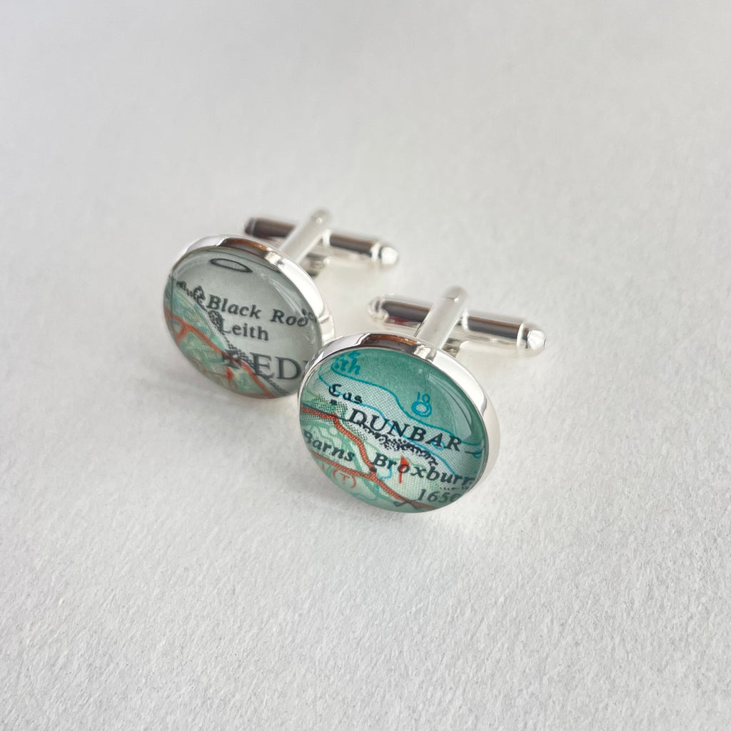 Map-themed cufflinks on a light gray background