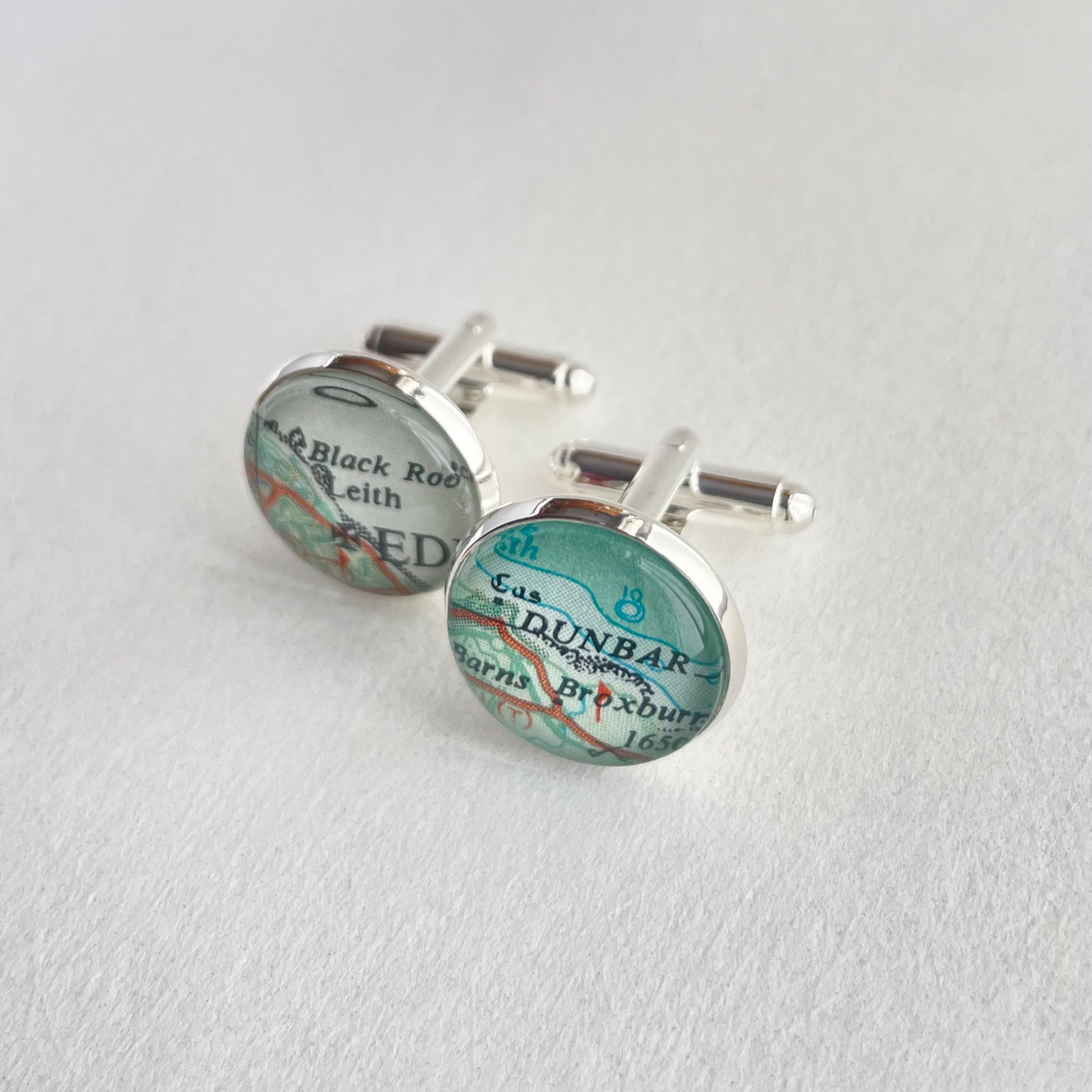 Map-themed cufflinks on a light gray background