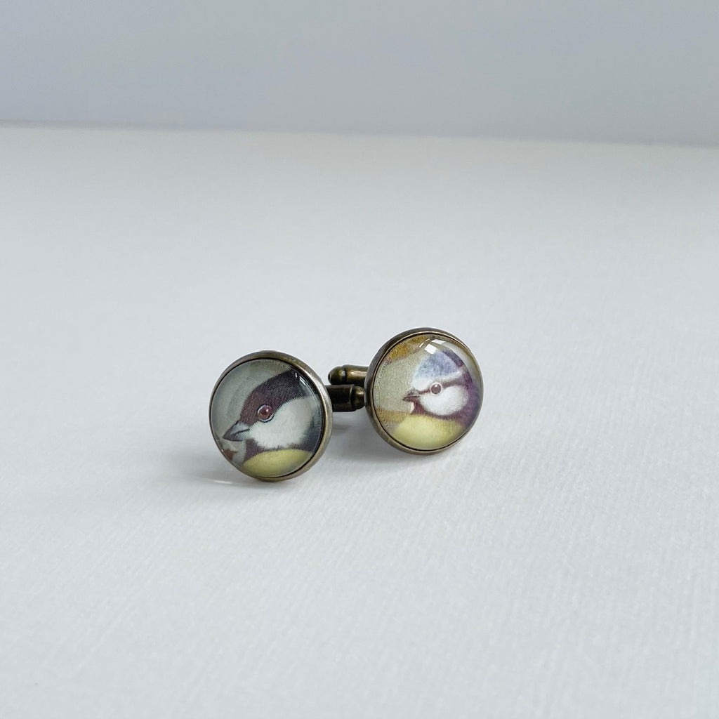 Circular bronze plated cufflinks set with vintage illustrations of british garden birds, under glass. They are against a white background