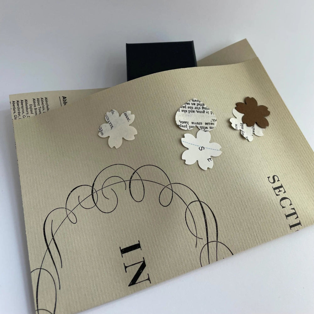 Decorative packaging with cut-out flowers and text on a white background