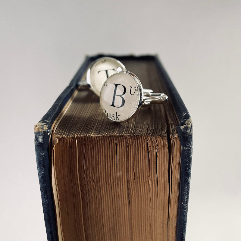 Cufflinks with 'B T' engraving on an open book