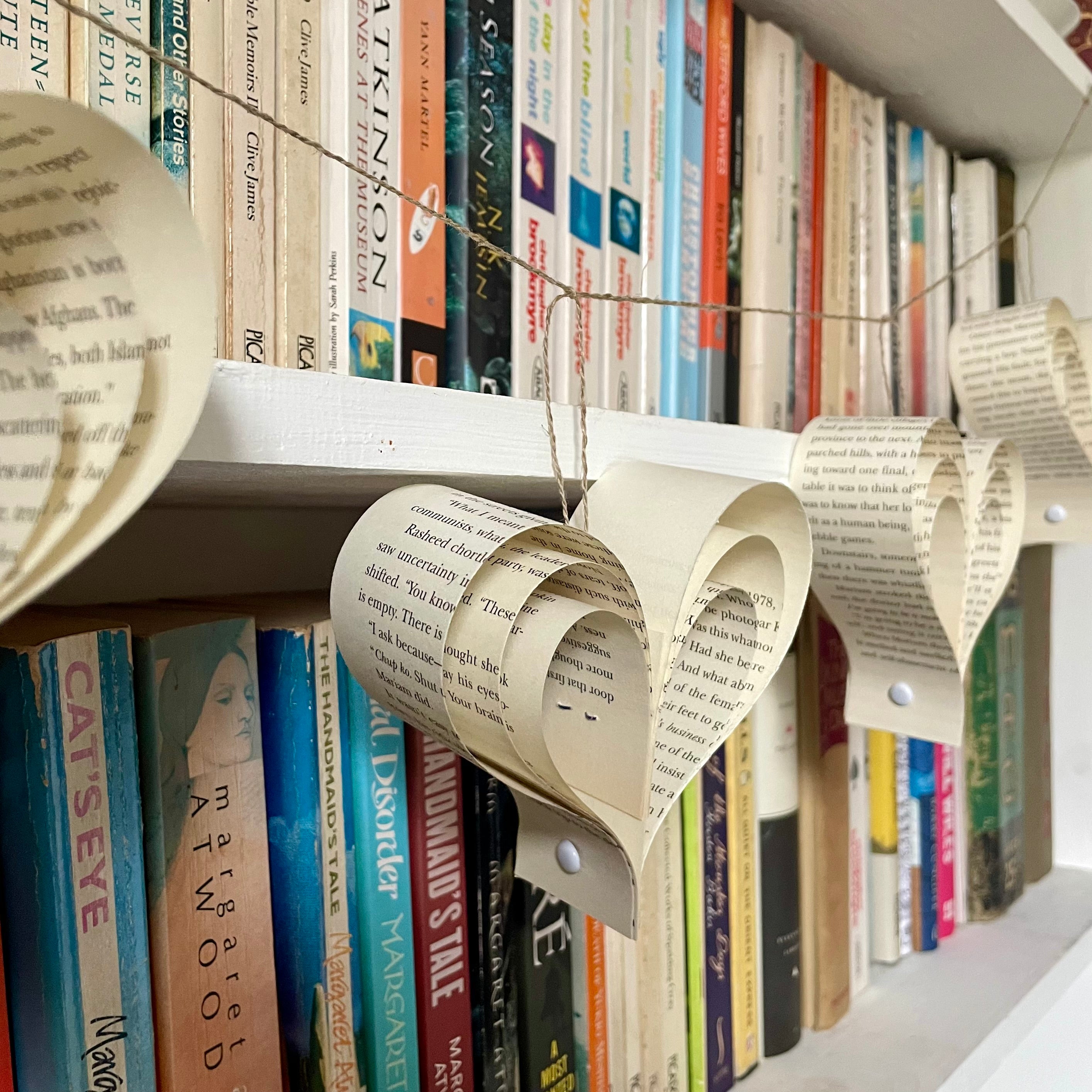 Decorative paper heart garland on a bookshelf with books in the background
