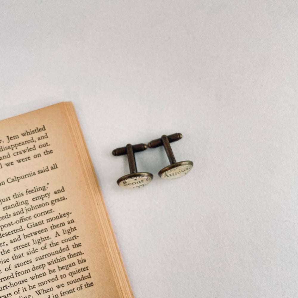 Cufflinks on an open book with a light background