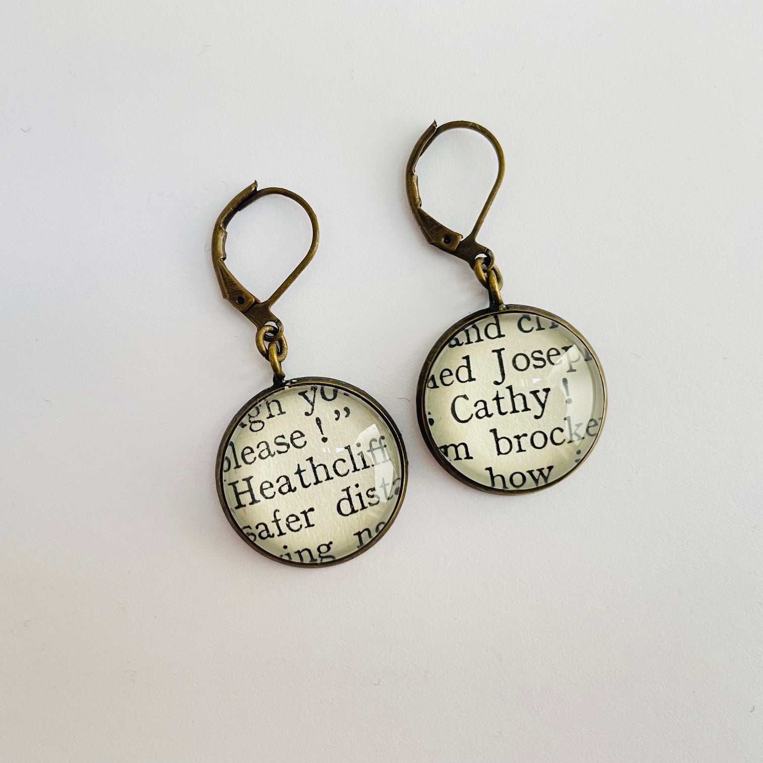 a pair of round bronze dangle earrings with 'Heathcliff' and 'Cathy' taken from real book pages. 