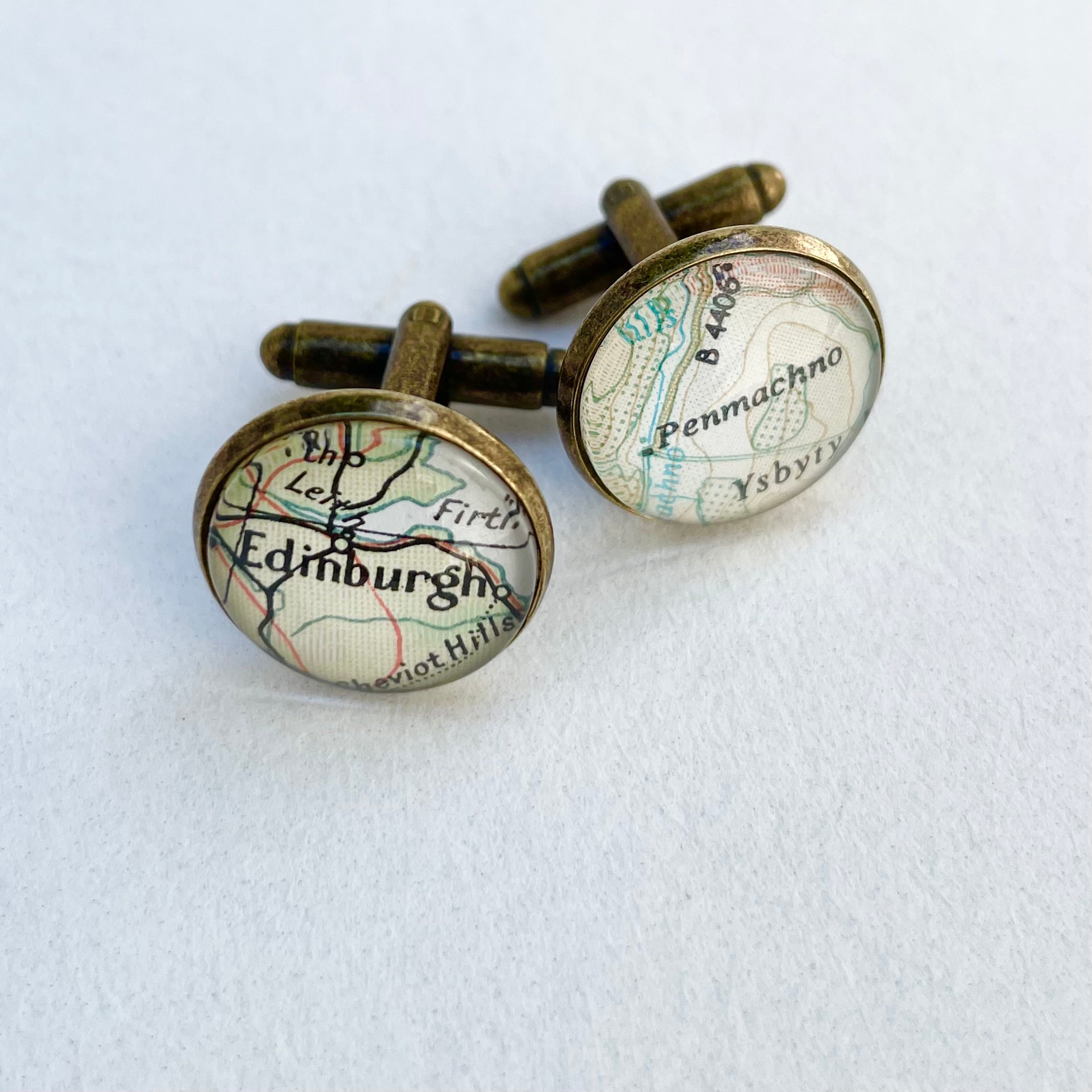 Map-themed cufflinks with 'Edinburgh' and 'Penmachno' on a white background