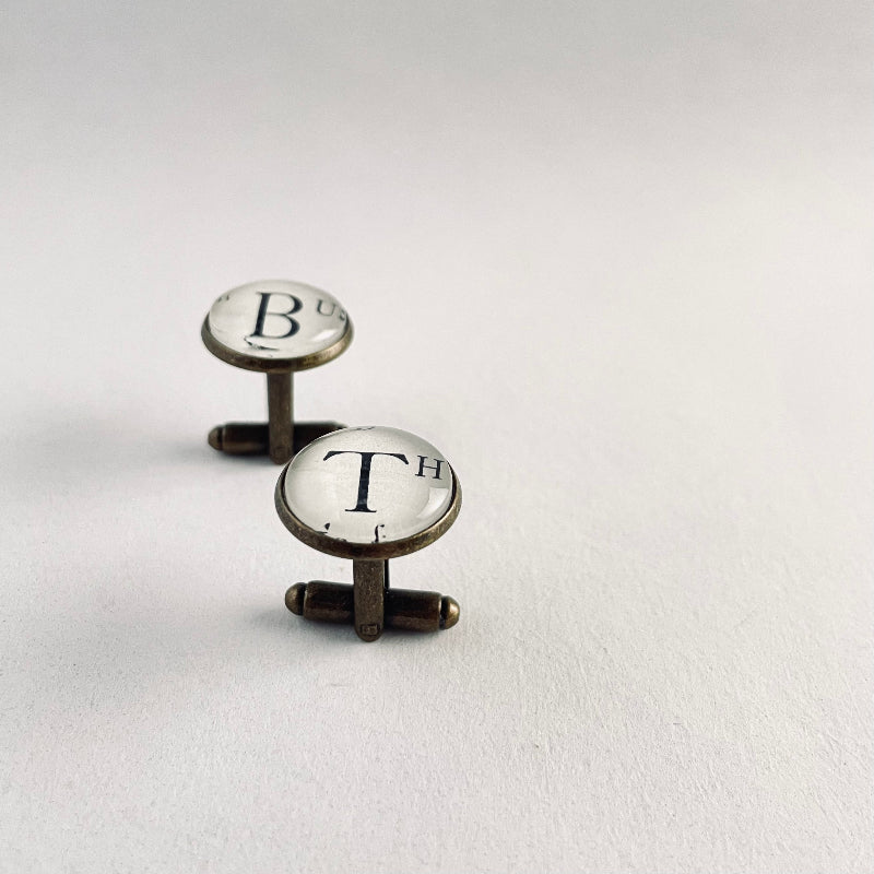 Cufflinks with 'B' and 'T' initials on a light gray background