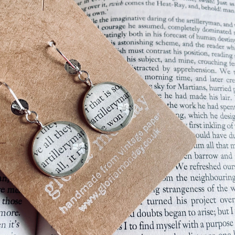 Pair of earrings with circular designs on a piece of paper with text
