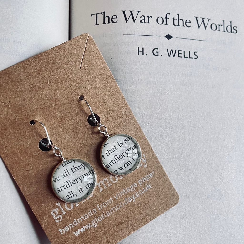 Pair of earrings with text design on a card with 'The War of the Worlds' by H.G. Wells in the background.