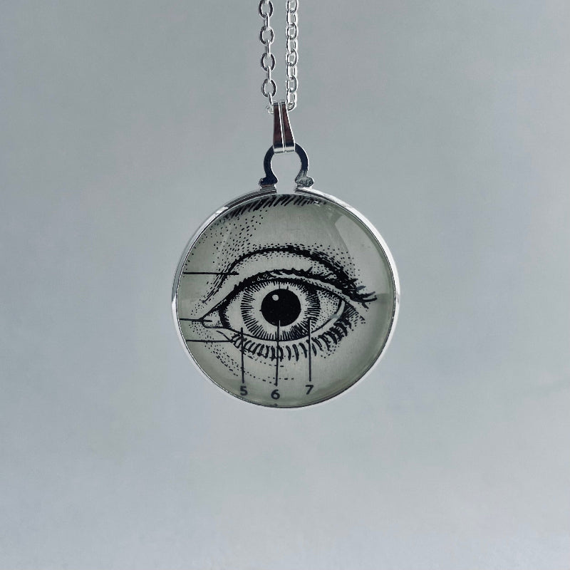 Pendant necklace with eye design on a gray background