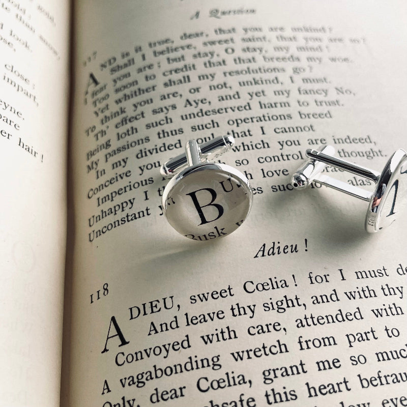 Silver custom cufflinks with a letter 'B' on an open book