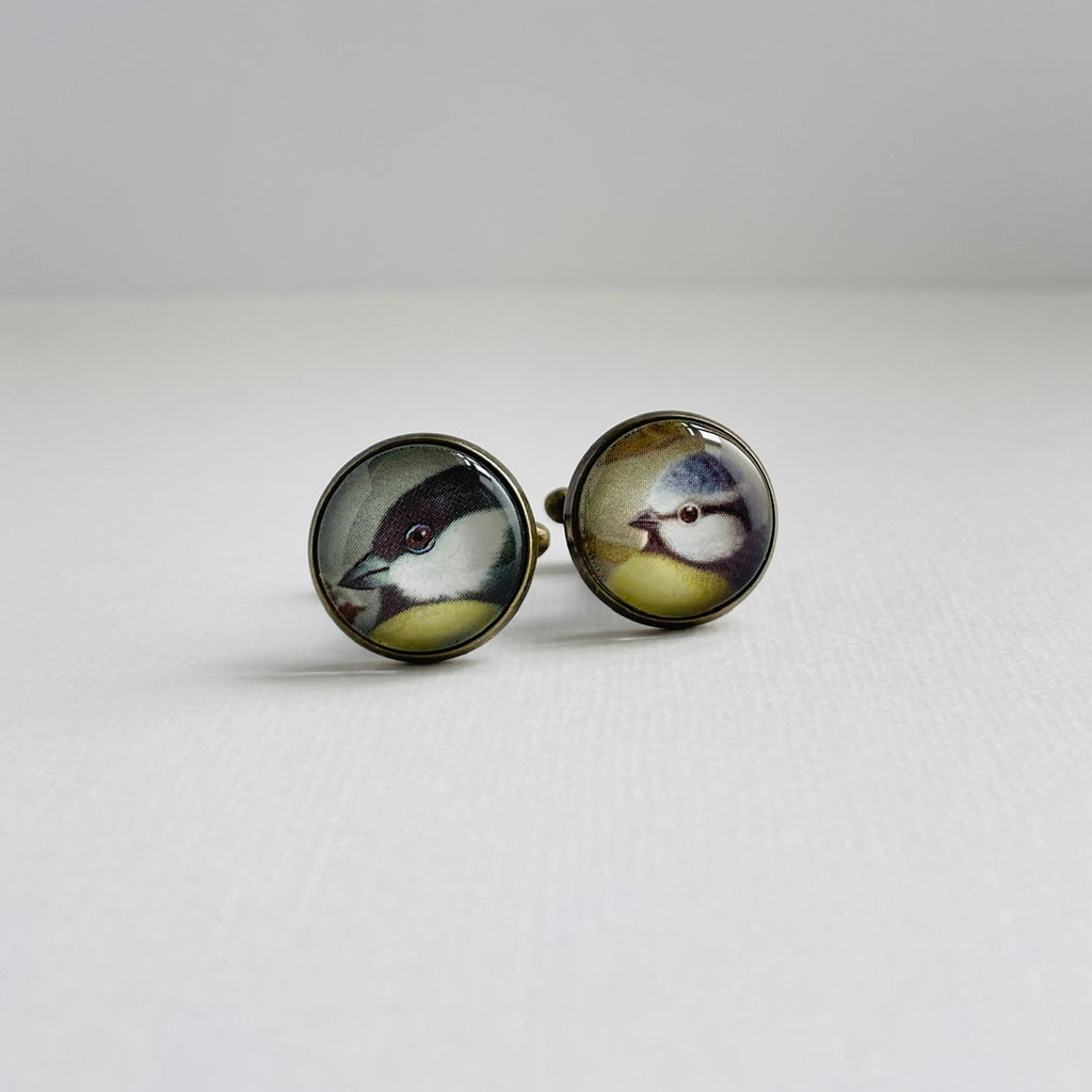 Circular bronze plated cufflinks set with vintage illustrations of british garden birds, under glass. They are against a white background