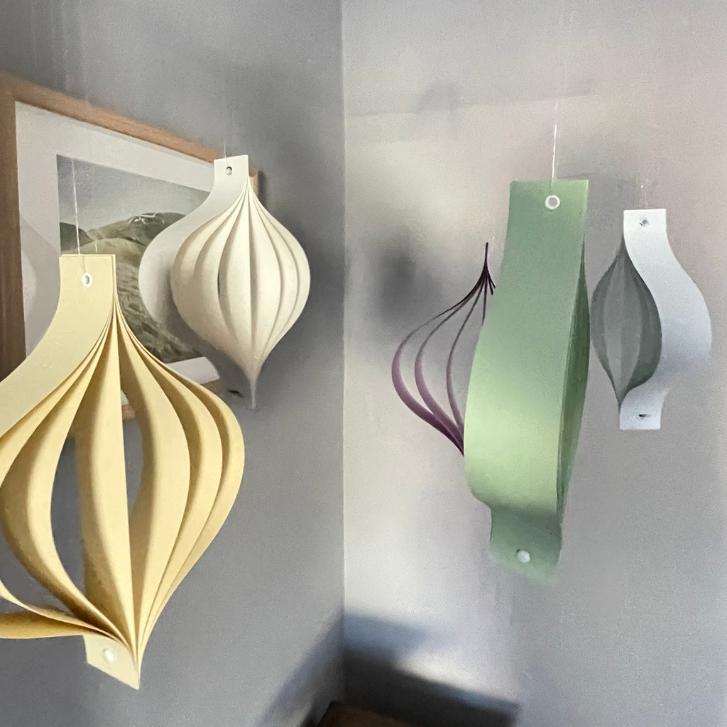 Pastel hanging decorative ornaments on a gray wall.