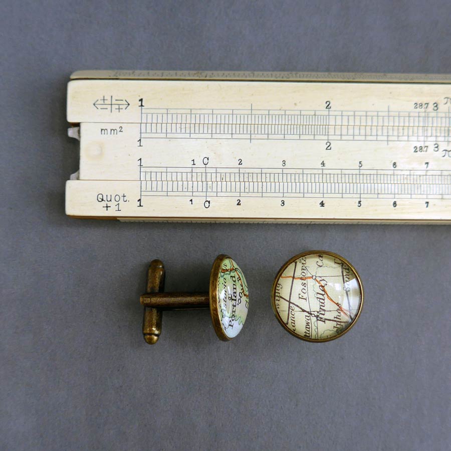 round bronze plated cufflinks customised with maps shown next to a ruler to show the dimension os 16mm in diameter